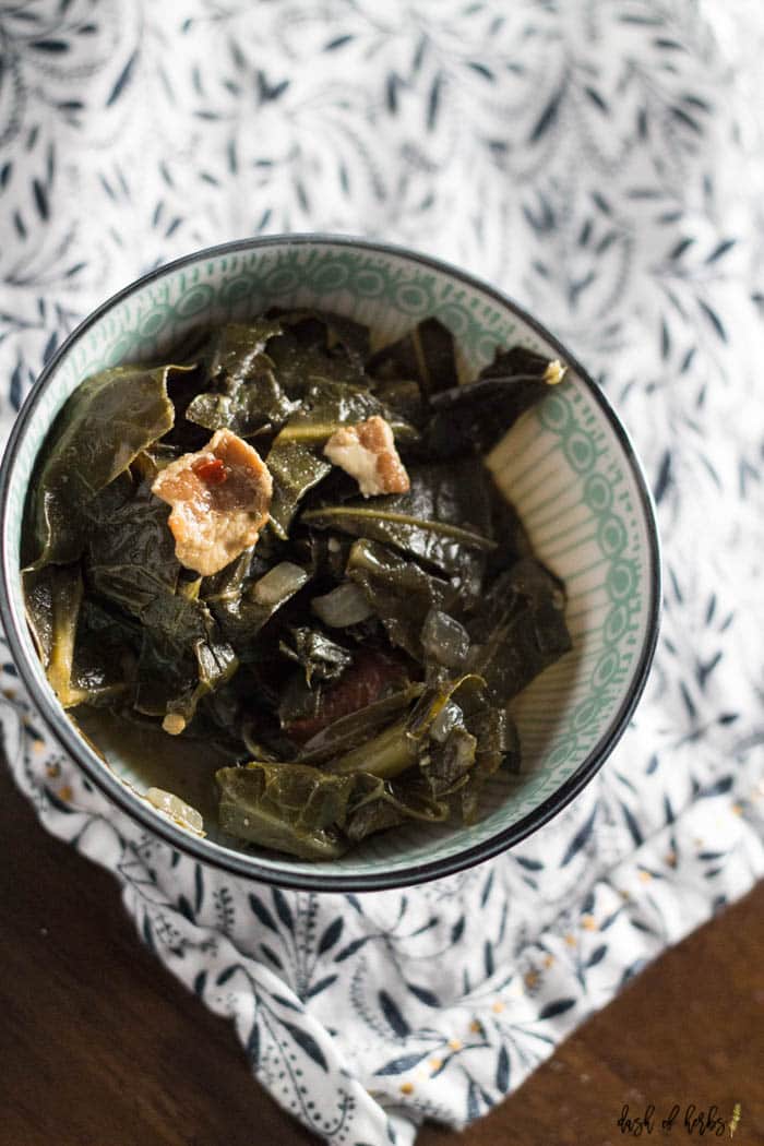 An overhead image of the One Pot Southern Collard Greens recipe that shows the collar greens in a decorate blue bowl.  You can see a white and navy napkin underneath the bowl.